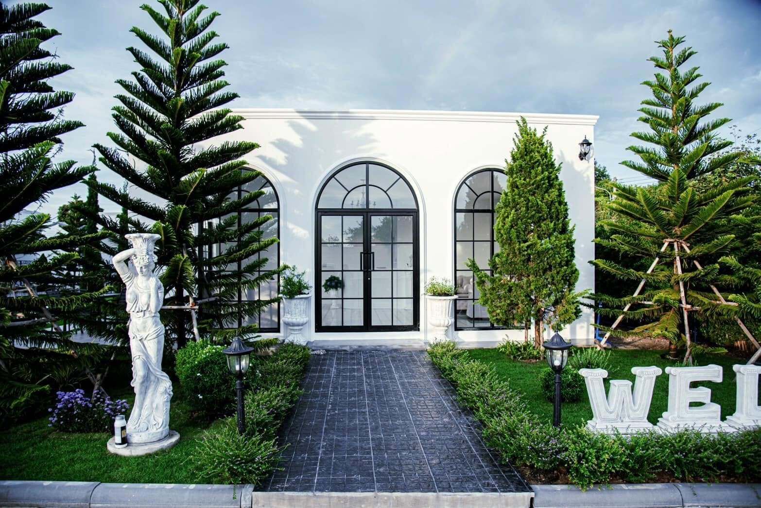 Un bâtiment doté d’une entrée centrale, flanqué de grands arbres et d’une statue.