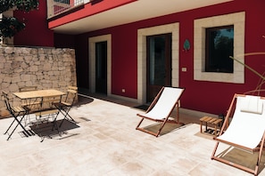 Eine Terrasse im Freien mit einer Steinmauer, einem Holztisch und zwei Liegestühlen.