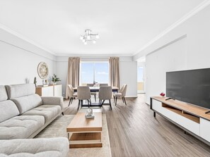 A modern living room with a sofa, dining table, chairs, and a TV. - Calheta Artlantic Pearl by Interhome (Calheta (Madeira))