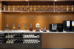 Een hotelbar met koffieautomaten, een koffiepers en diverse mokken en bekers.