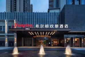 A hotel entrance with a fountain, a sign reading 'Hampton,' and a modern building facade. - Hampton by Hilton Huizhou HuiyangDayaBay (Huizhou)
