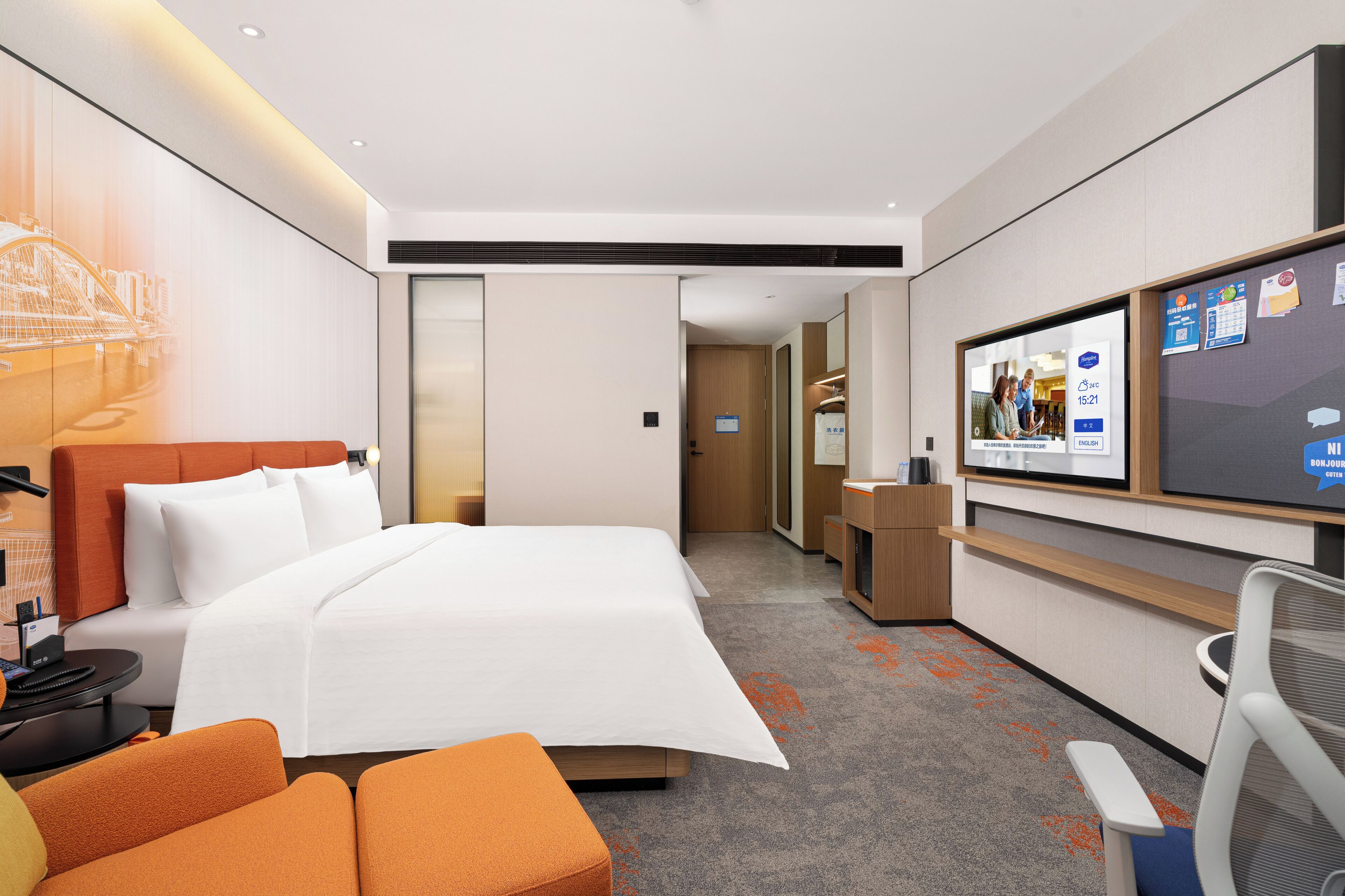 Une chambre d’hôtel moderne dotée d’un grand lit, d’un bureau avec un ordinateur, d’une télévision et d’un coin salon.