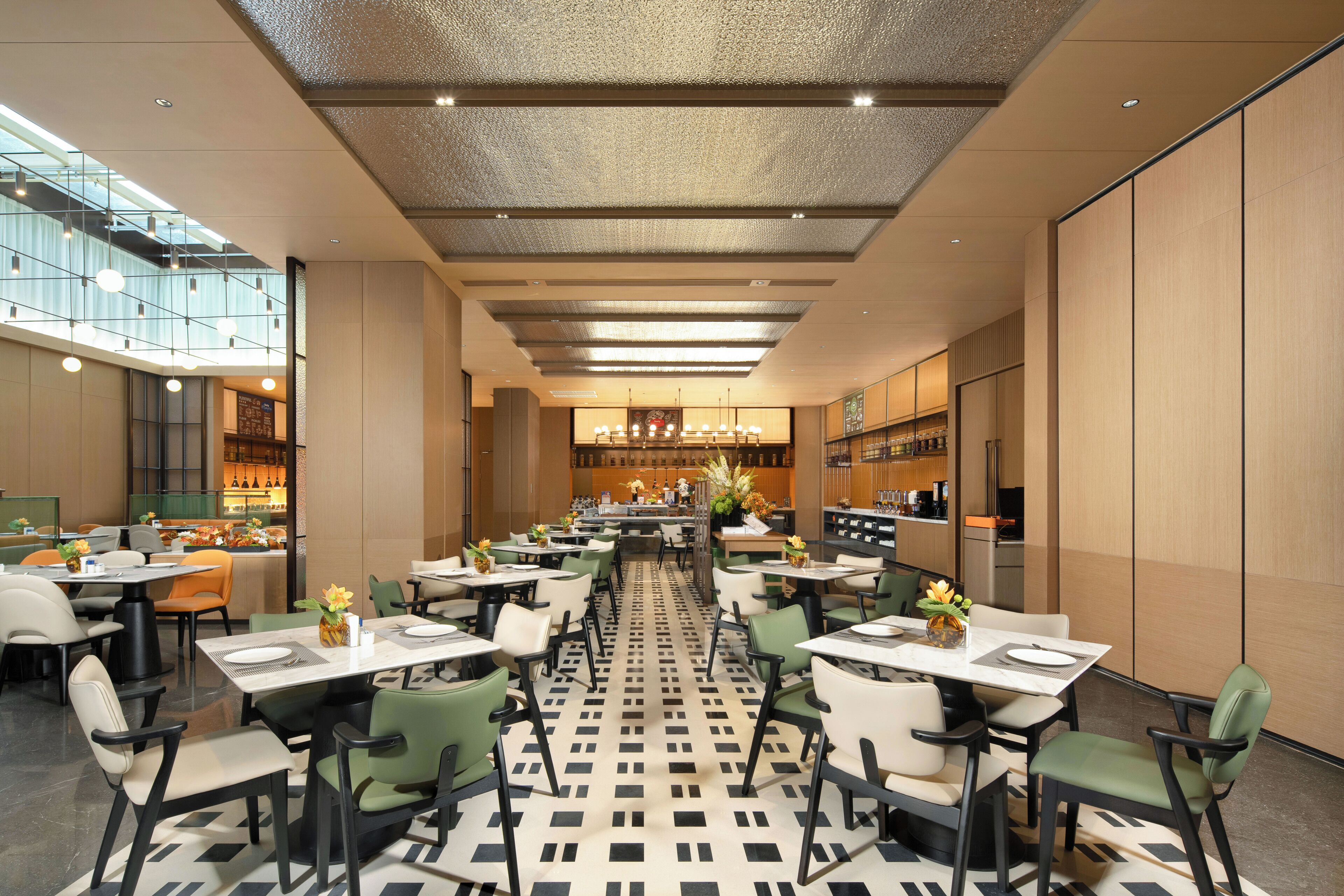 Un espace repas moderne avec plusieurs tables et chaises, un sol à motifs et une cuisine en arrière-plan.