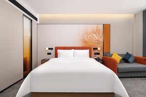 Een moderne hotelkamer met een groot bed, een slaapbank en een tv aan de muur.