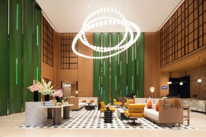 Um hall moderno com balcão de recepção, área de estar e luminária decorativa.