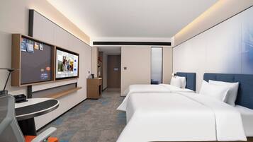 A modern hotel room with a large bed, a desk with a chair, a flat-screen TV, and a bathroom visible through an open door.