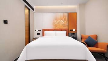 A hotel room with a large bed, a nightstand, a chair, and a wall-mounted TV.