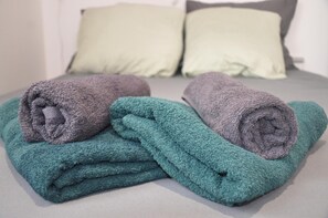 Ein ordentlich bezogenes Bett mit zwei Kissen und zwei zusammengerollten Handtüchern.