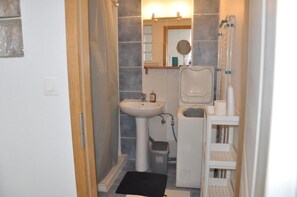 A compact bathroom with a pedestal sink, a mirror, a toilet, and a small trash bin. - 'F1 Fully Equipped Apartment Near Tram - Jungle' with Wi-Fi and Air Conditioning (Mulhouse)