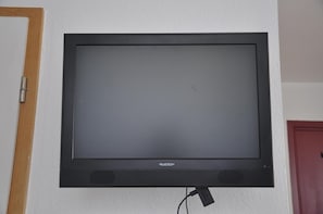 A flat-screen TV mounted on a wall with a visible brand label.