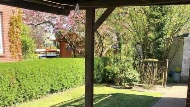 A covered patio area with a brick pathway, a table, and chairs. - Ferienhaus an der Mühle (Krummhörn)