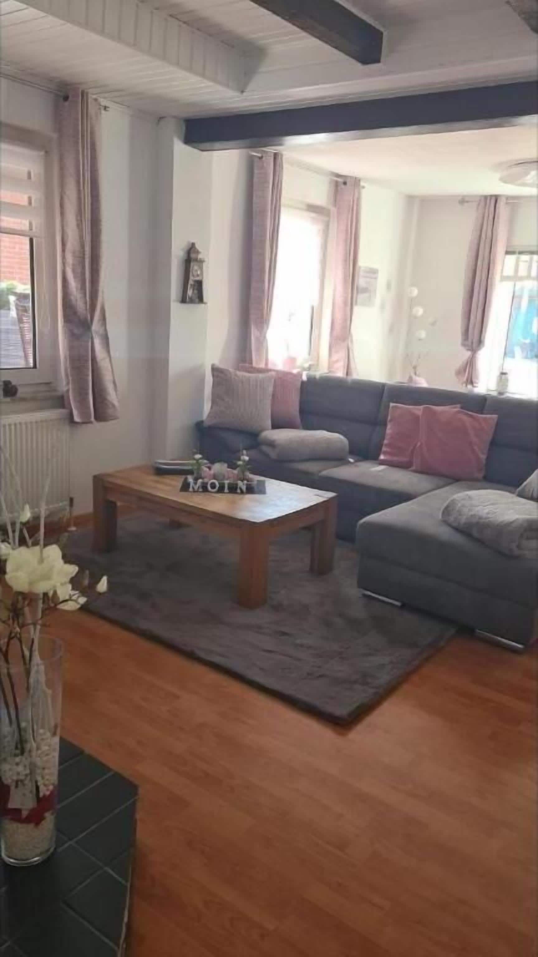 Ein Wohnzimmer mit einer Couch, einem Couchtisch und einer Vase mit Blumen.