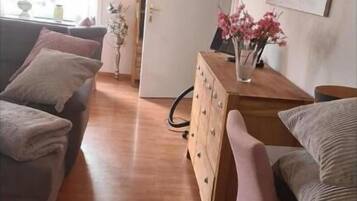 Ett vardagsrum med en soffa, en byrå i trä och en stol.
