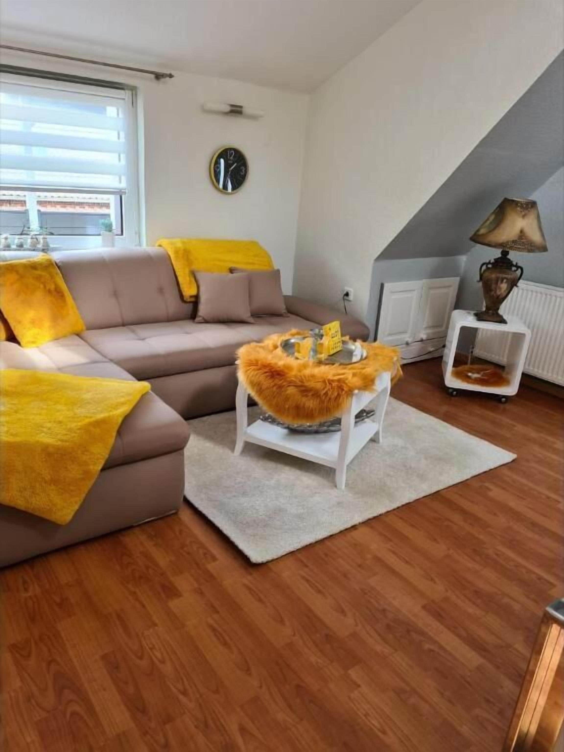 Ein Wohnzimmer mit einer Couch, einem Couchtisch, einer Lampe und einer Wanduhr.