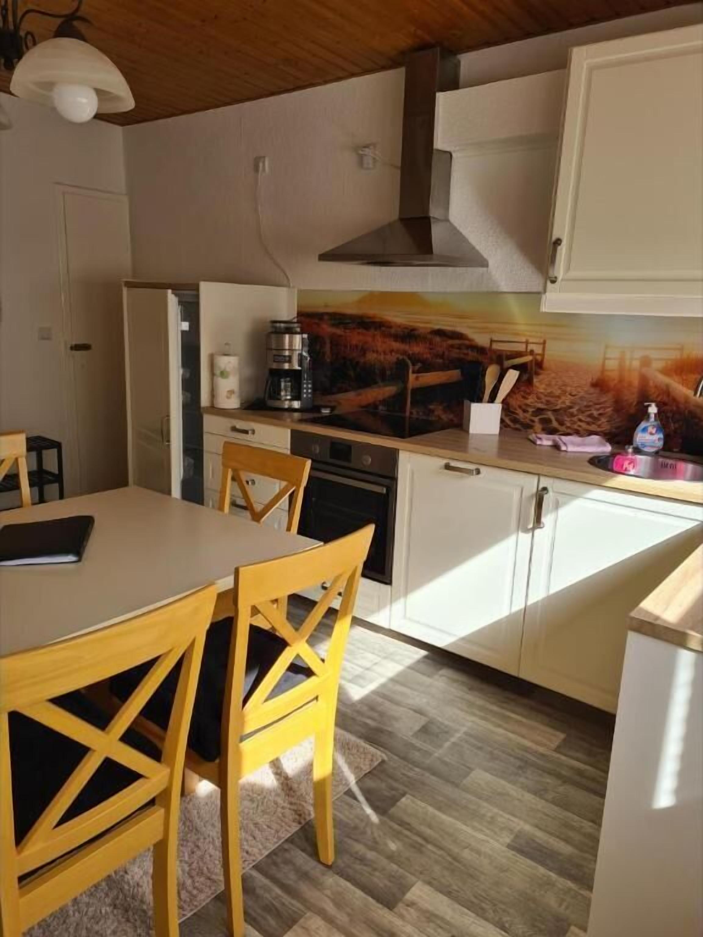 Una cocina compacta con gabinetes blancos, una mesa de comedor de madera y sillas.