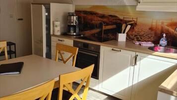 Una cocina compacta con gabinetes blancos, una mesa de comedor de madera y sillas.