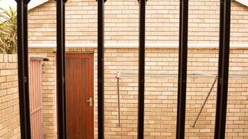 A brick building with a wooden door, a metal gate, and a bird feeder on the wall.