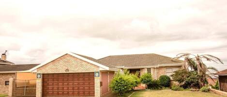 A residential house with a brick facade, a garage, and a well-maintained lawn.