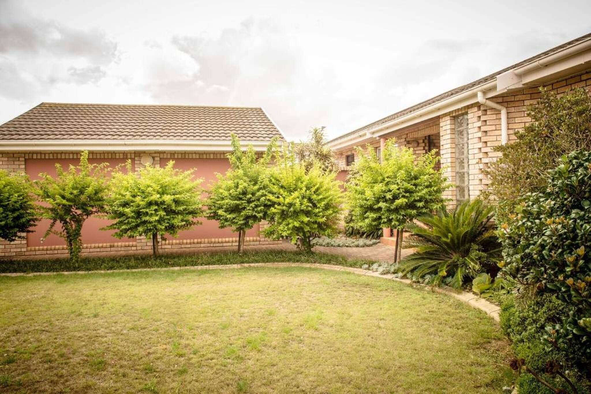 A courtyard with a brick building, green trees, and a well-maintained lawn.