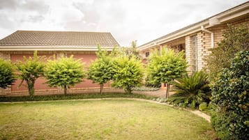 A courtyard with a brick building, green trees, and a well-maintained lawn.