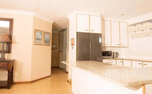 A kitchen with white cabinets, a stainless steel refrigerator, a microwave, and a coffee maker.