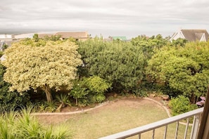 A residential garden with various trees and a lawn. - Charming 4-bedroom Apartment in Jeffreys Bay, South Africa (Jeffreys Bay)