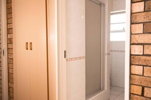 A room with a sliding door, a tiled floor, and a brick wall.