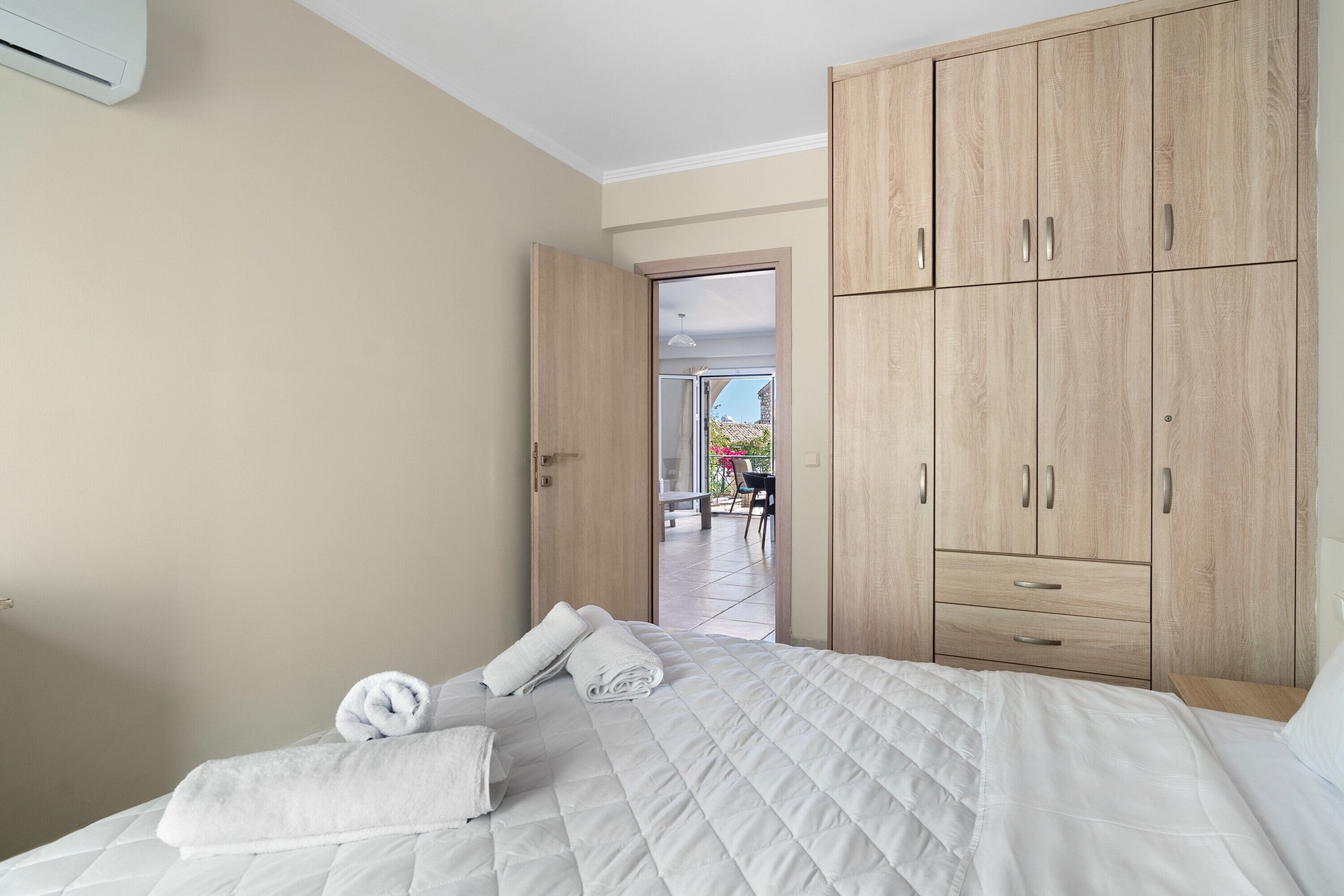 Een slaapkamer met een bed, een kledingkast en een deur naar een buitenruimte.