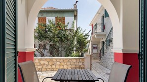 Zona d'estar a l'exterior amb taula i cadires, un mur de pedra i vista d'un edifici amb balcó.