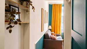 A narrow hallway with a sofa, a plant, and a framed picture on the wall. - CHICKY HOUSE (Paris)