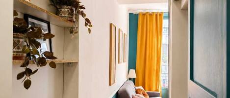 A narrow hallway with a sofa, a plant, and a framed picture on the wall.