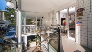 A hotel lobby with a staircase, a view of the street, and a sign indicating the hotel name.