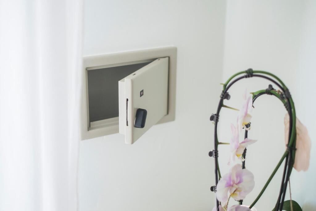 A white wall with a light switch and a small window.
