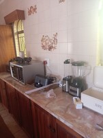 Una cocina con microondas, tostadora, licuadora y cafetera sobre la encimera.