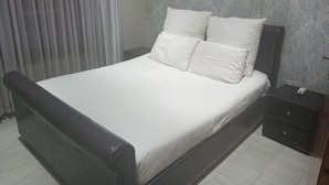A neatly made bed with white bedding, a dark headboard, and a small bedside table with a lamp. - Luxurious 4-bedroom House Rental With Pool Access in Ngaka Modiri Molema (Mahikeng)