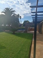 Un espacio exterior bien cuidado con césped, palmeras y una estructura de ladrillo.