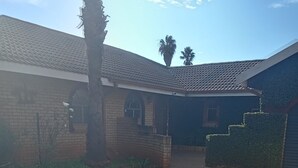 A residential property with a paved driveway, a brick wall, a gated entrance, and a small garden area. - Luxurious 4-bedroom House Rental With Pool Access in Ngaka Modiri Molema (Mahikeng)