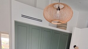 Ett sovrum med en säng, en garderob, en hängande lampa och utsikt över omgivningarna.