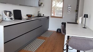 Ett modernt kök med grå skåp, ett matbord i trä och en bardisk.