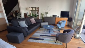 Ett modernt vardagsrum med en soffa, fåtöljer, ett soffbord och en tv.