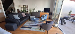 Ein modernes Wohnzimmer mit einer Couch, Sesseln, einem Couchtisch und einem Fernseher.