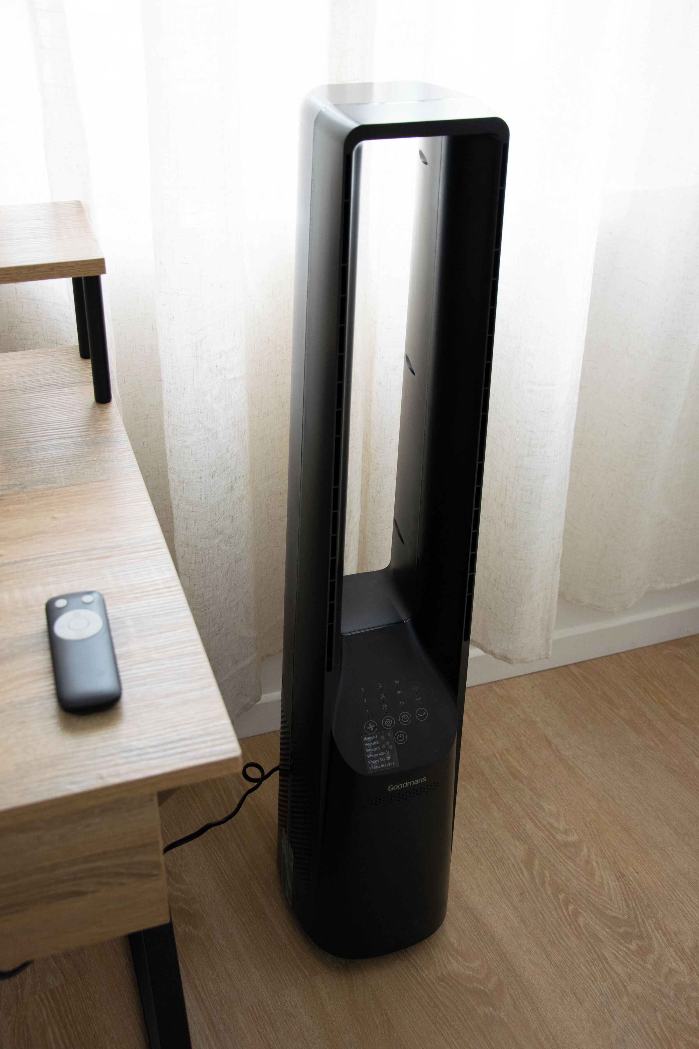 Ein schwarzes elektronisches Gerät auf einem Holztisch, neben ihm eine Fernbedienung.