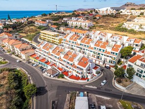 Ein Wohngebiet mit modernen Mehrfamilienhäusern, einer Straße und Blick aufs Meer.