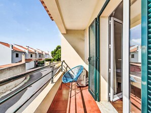 A balcony with a chair, a sliding door, and a view of neighboring buildings. - Casa da Abegoaria by Interhome (Caniço (Madeira))