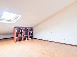 A room with a sloped ceiling, a skylight, a wooden bookshelf, and a tiled floor. - Casa da Abegoaria by Interhome (Caniço (Madeira))