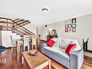 A modern living room with a grey sofa, wooden dining table, and a staircase. - Casa da Abegoaria by Interhome (Caniço (Madeira))