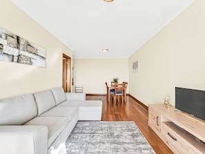 A modern living room with a sofa, a TV, a wooden cabinet, and a dining area with chairs and a table. - Apartment Baly Formosa by Interhome (Funchal (Madeira))