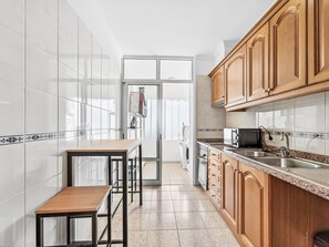 A kitchen with white tiles, wooden cabinets, a stainless steel sink, and a built-in oven. - Apartment Baly Formosa by Interhome (Funchal (Madeira))
