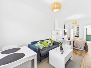 A modern living room with a grey sofa, white coffee table, and a white bookshelf. - Panoramic Studio View by Interhome (Funchal (Madeira))