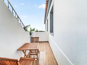 A narrow balcony with a wooden table and chairs, a white wall, and a window. - Panoramic Studio View by Interhome (Funchal (Madeira))